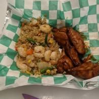 Takeout food in a green-and-white checkered basket liner, with fried rice, shrimp, and chicken wings