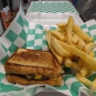 Grilled sandwich and crinkle-cut fries in a green-and-white checkered basket liner