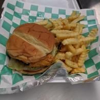 Burger and crinkle-cut fries in a tray lined with green-and-white checkered paper.