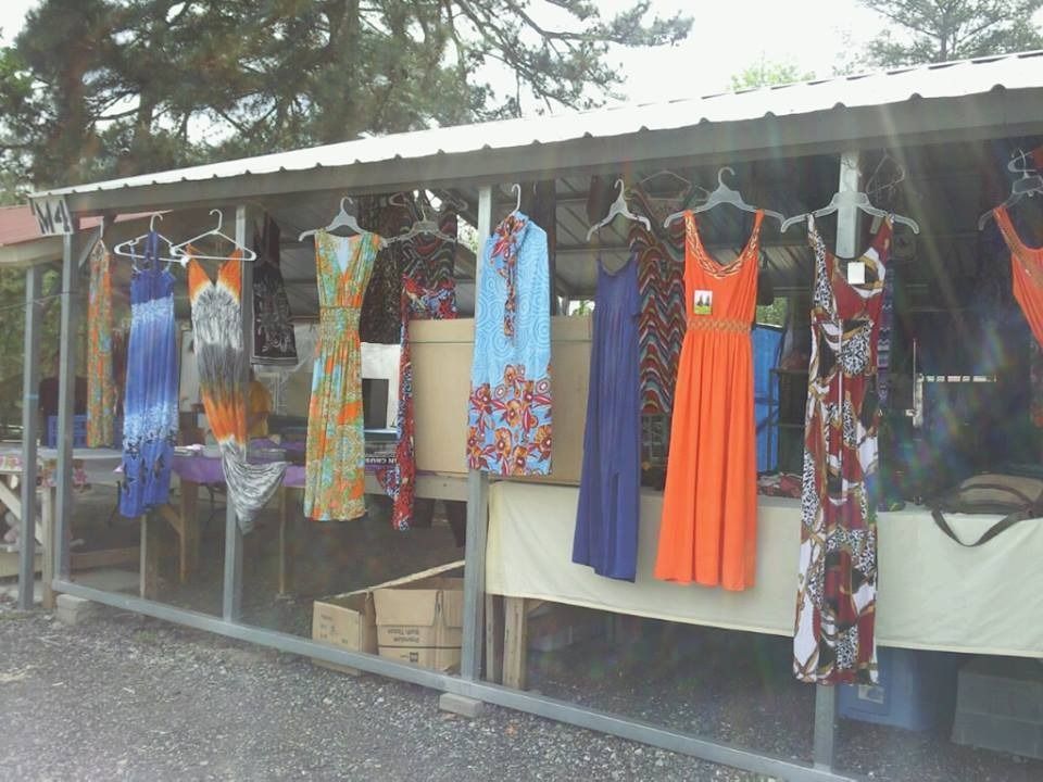 Outdoor clothing stall with colorful dresses hanging under a roof by a roadside