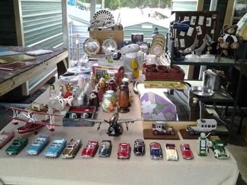 Tabletop display of miniature cars, toys, and collectibles arranged indoors on a long table
