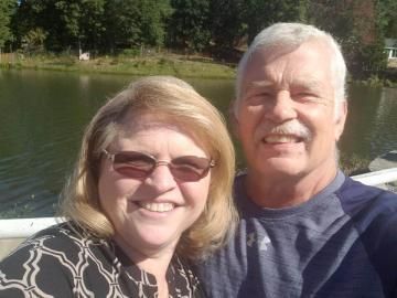 Smiling couple taking a selfie by a lake on a sunny day