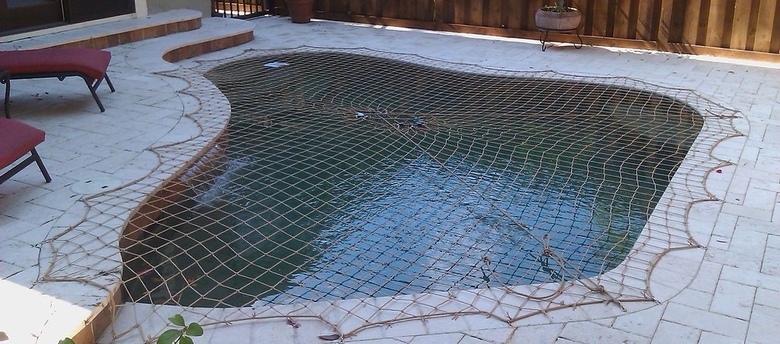 A large swimming pool is sitting on a patio next to a fence.