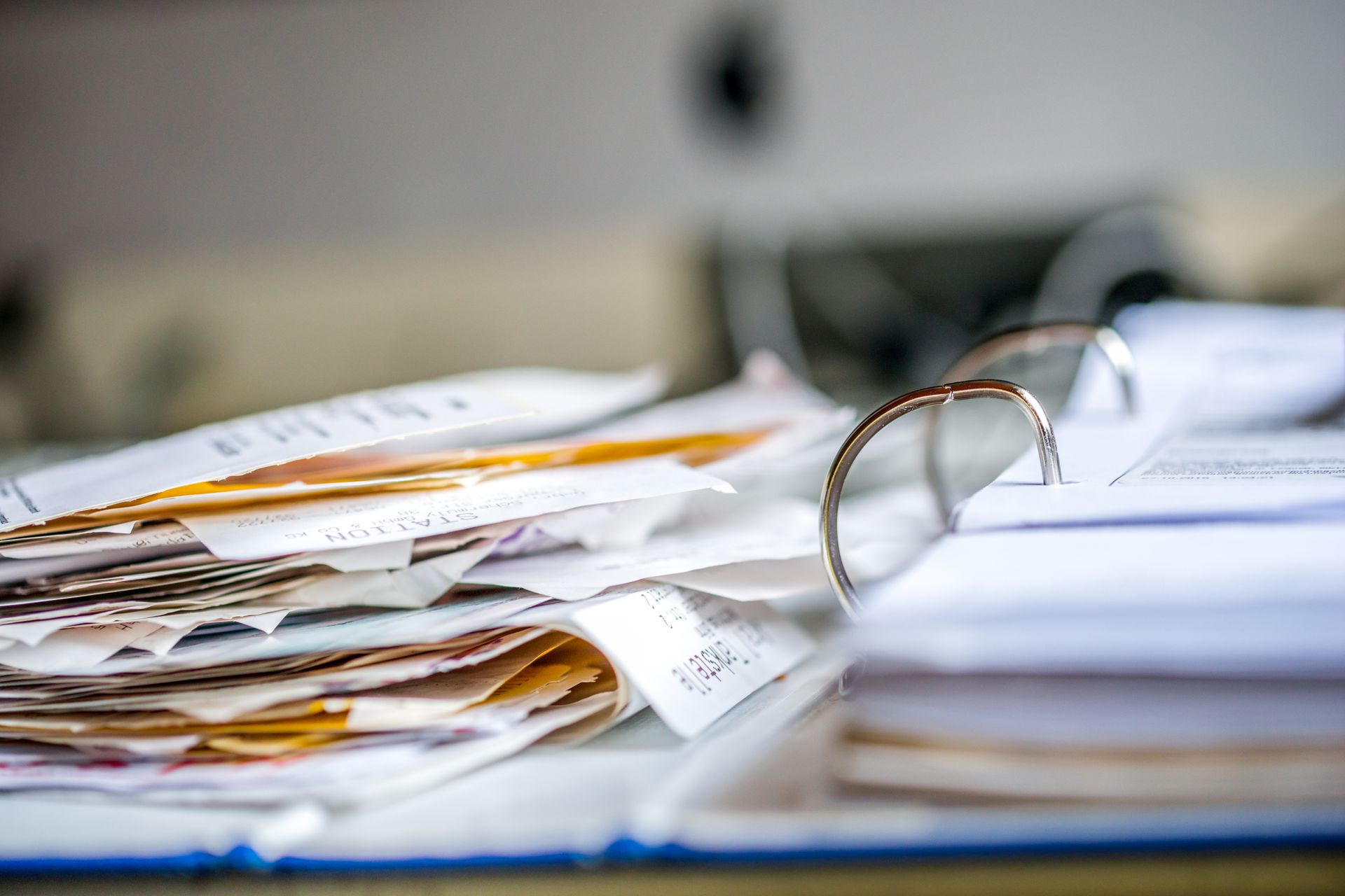 Close-up of open binder filled with a messy stack of various documents, papers, and receipts.