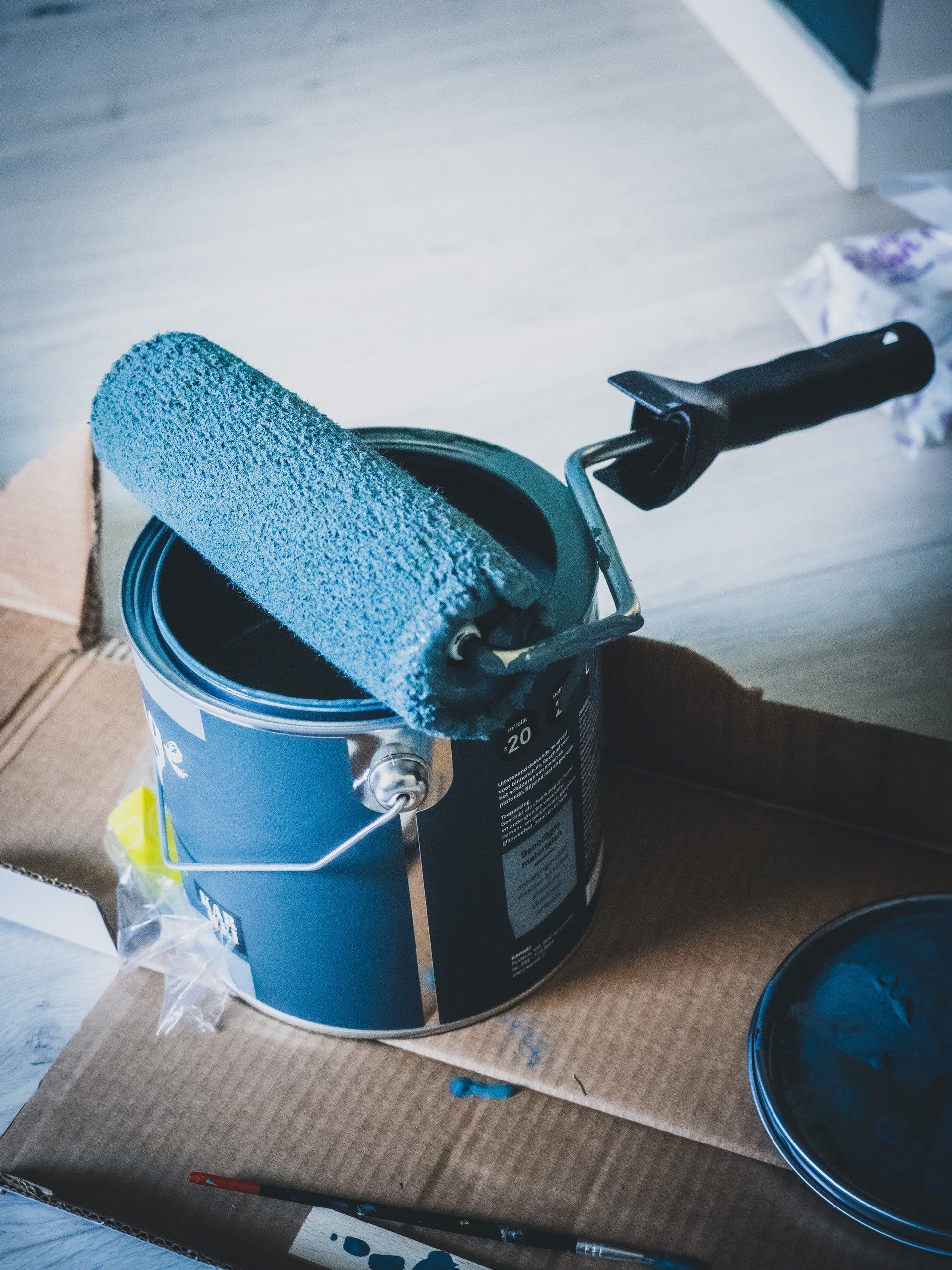 a blue paint can with a paint roller in it