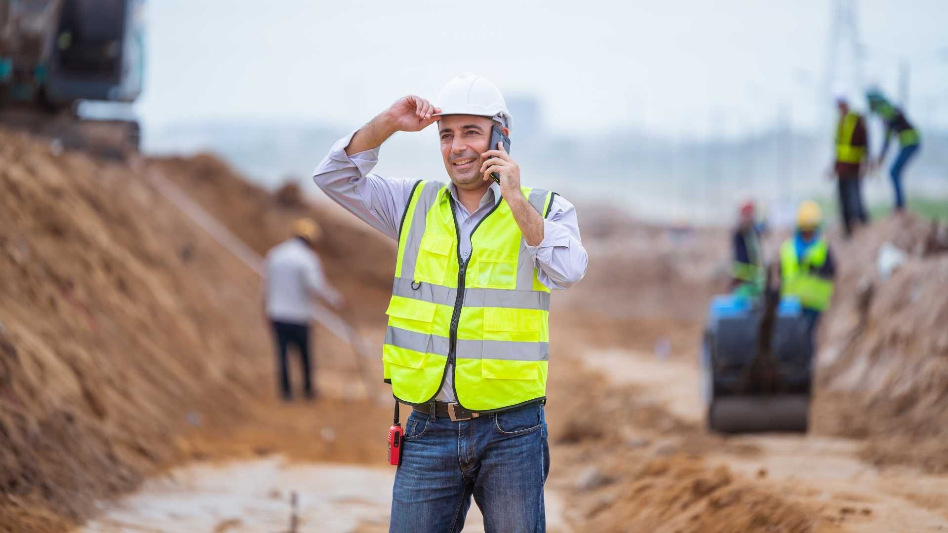 A construction worker is talking on a cell phone at a construction site.