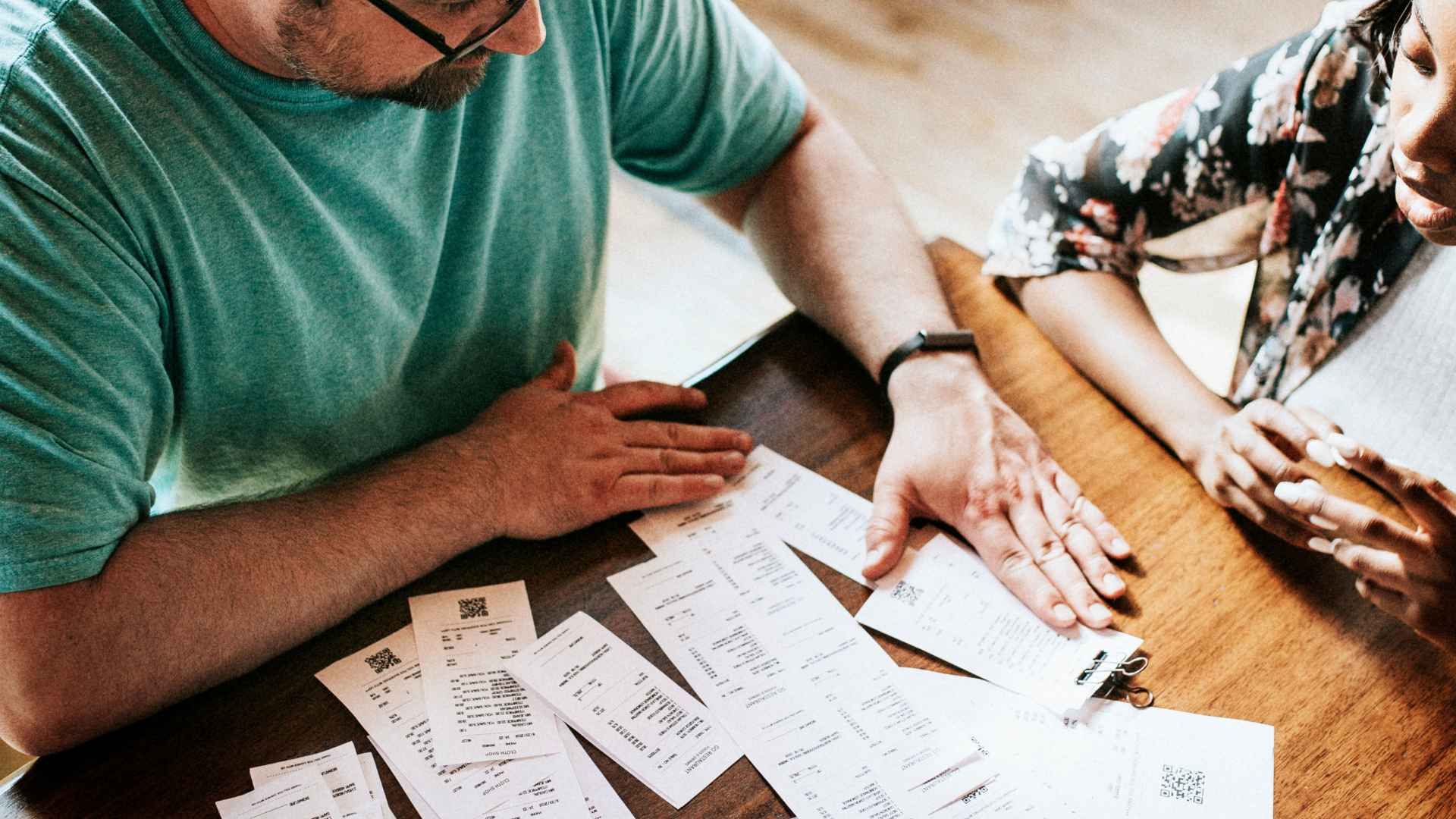 A man and a woman are sitting at a table looking at papers.