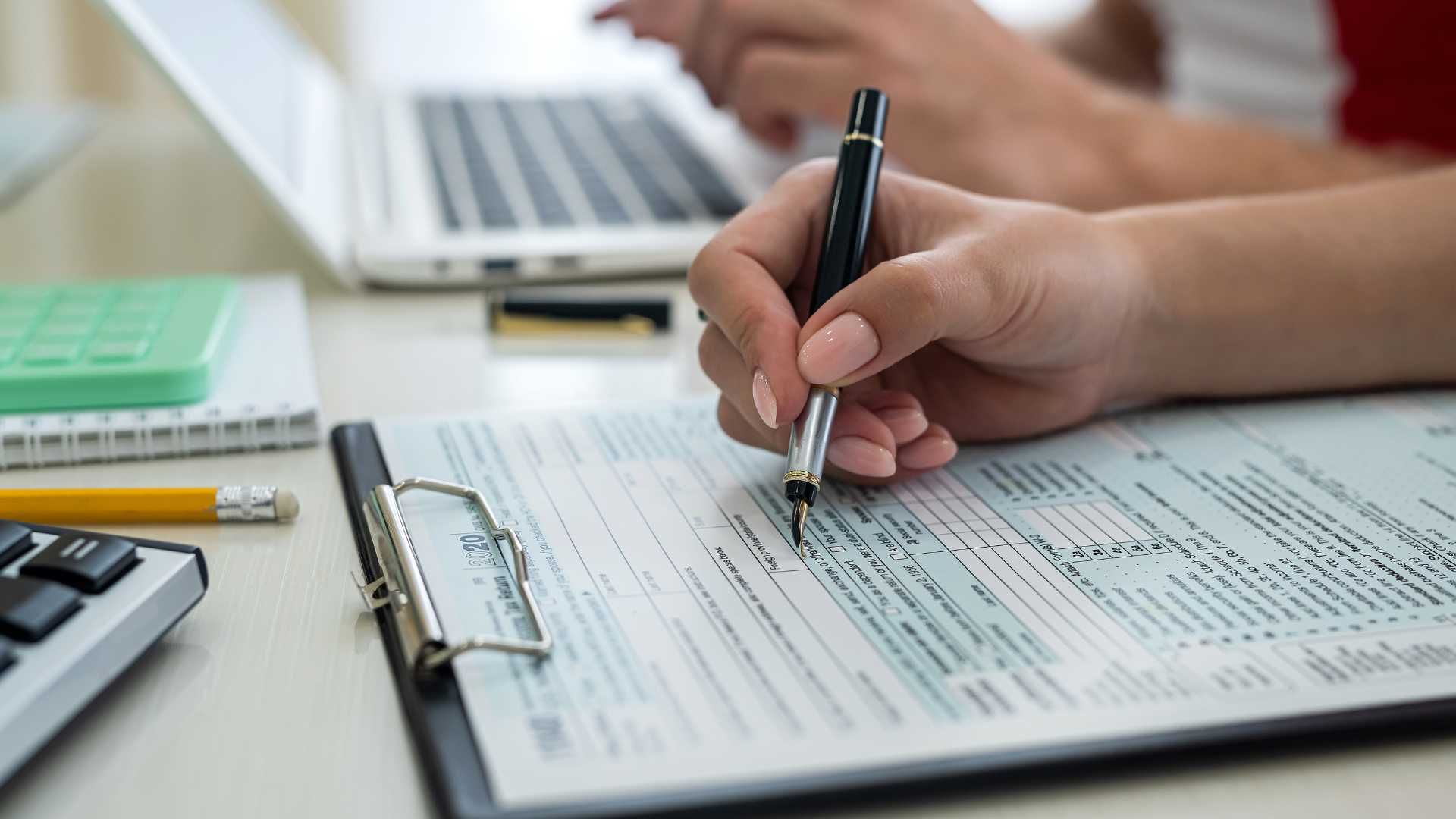 A person is writing on a clipboard with a pen.
