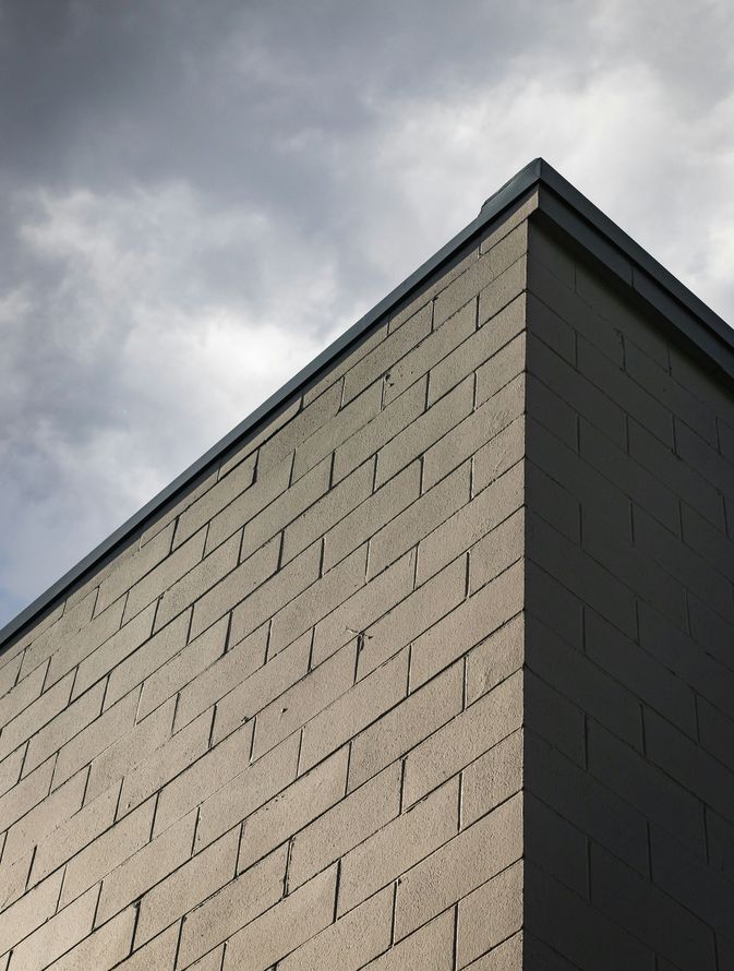 Corner of a beige brick building against a cloudy gray sky