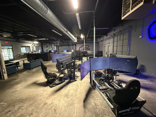 Indoor go-kart racing track with several black and blue karts in a dimly lit garage-like space