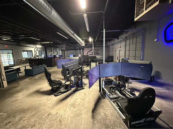 Indoor esports gaming setup with multiple racing simulators and large curved monitors in a dim room
