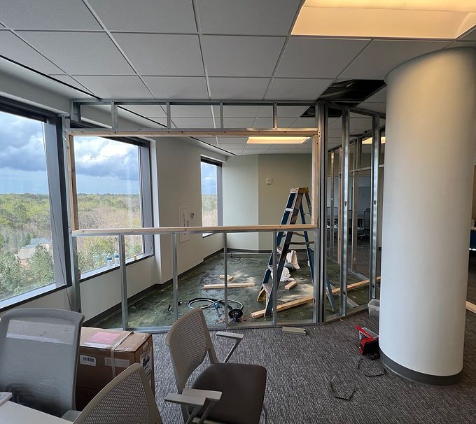 Office corridor under renovation with ladder, tools, and construction materials near windows