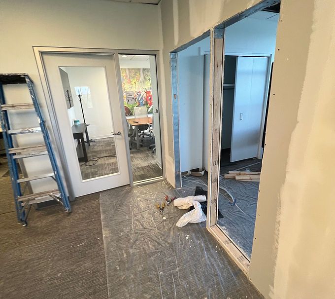 Renovation site with ladder, open doorway, and construction debris in a hallway
