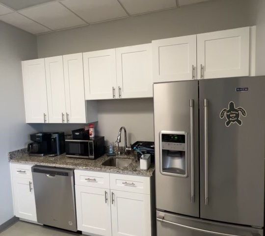 Modern kitchen with white cabinets, stainless steel appliances, and a countertop coffee maker