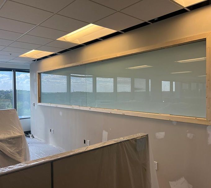 Office under renovation with frosted glass wall, drop ceiling, and covered furniture