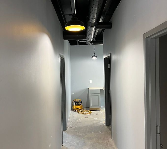 Empty hallway under construction with exposed ceiling lights and debris on the floor