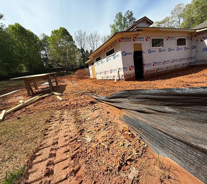 Partially built house with wrapped exterior and dirt construction site in the foreground