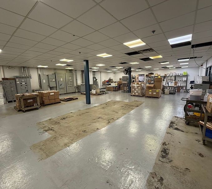 Empty warehouse interior with concrete floor, stacked boxes, and fluorescent ceiling lights