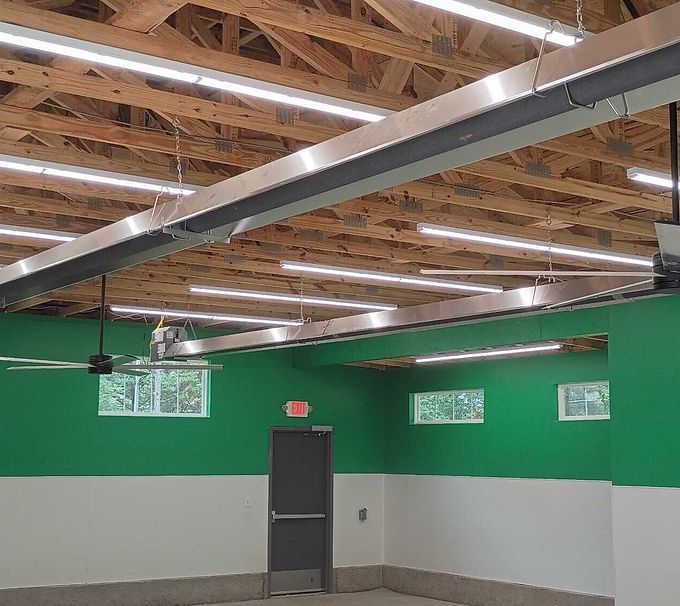 Industrial room with green and gray walls, exposed ceiling beams, overhead lights, and a central door