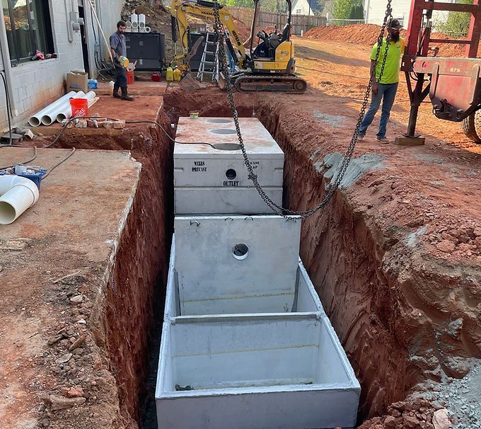 Workers installing concrete utility boxes in a trench at a construction site