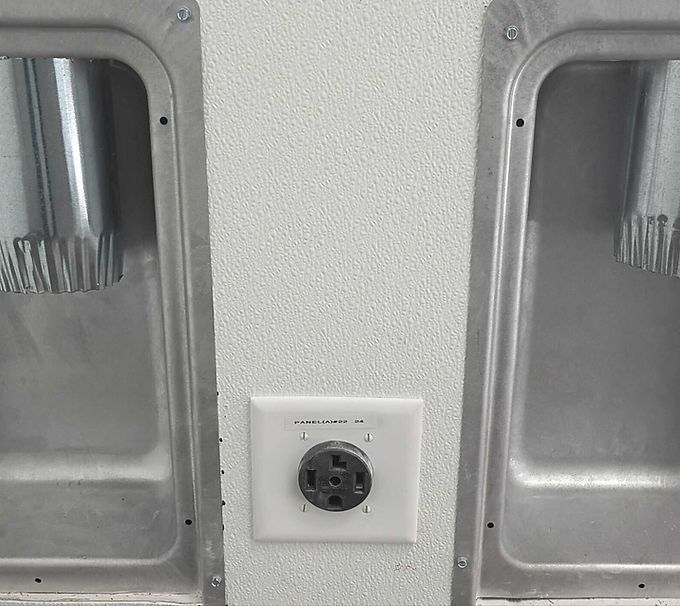 Stainless steel wall alcoves flanking a black electrical outlet on a light textured wall.