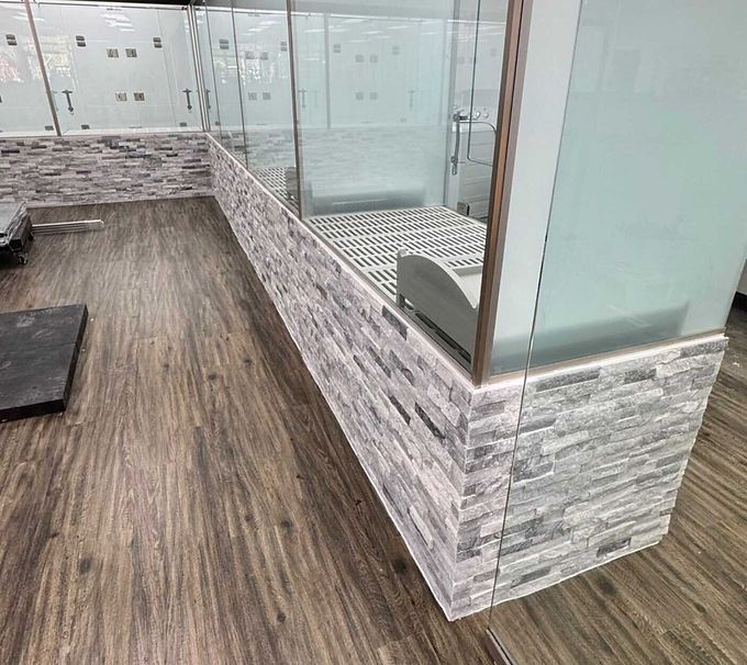 Modern patio with wood-look flooring and frosted glass railing beside a tiled hot tub area