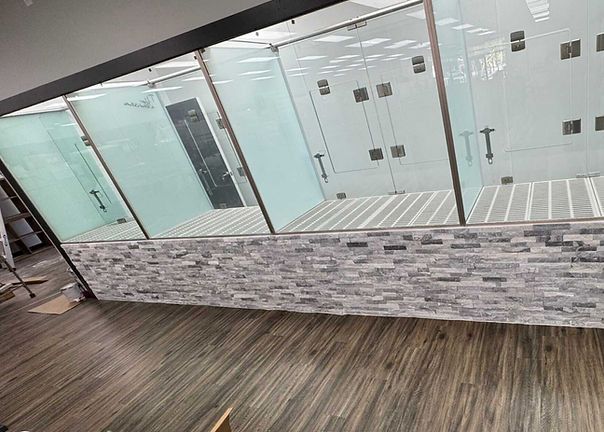 Modern office lobby with glass doors and a stone front counter on wood-look flooring