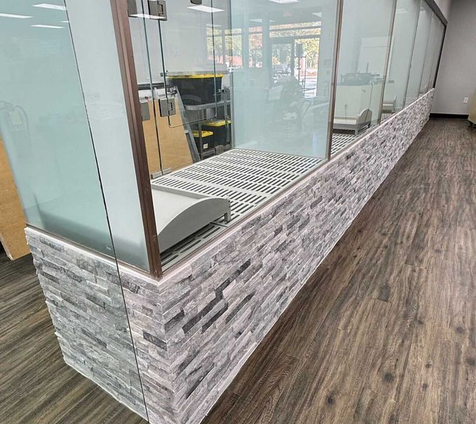 Glass display case with stone tile base in a wood-floored interior.