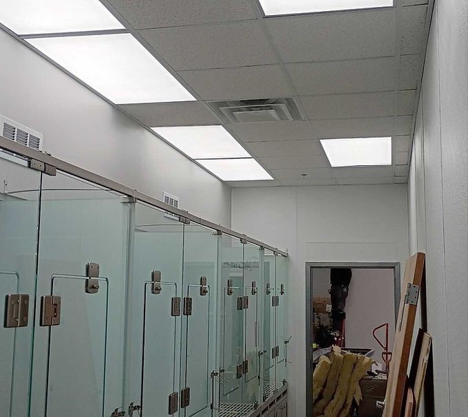 Bright hallway with glass shower stalls and ceiling lights in a locker-room-like interior