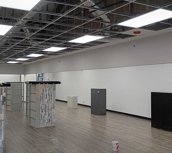 Empty retail interior with unfinished ceiling, white walls, and wood-look flooring