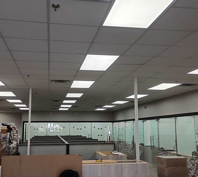 Empty office interior with fluorescent ceiling lights, glass partitions, and cubicles