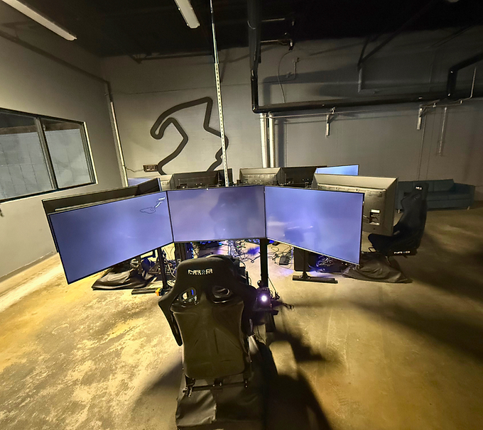 Gaming setup with five curved monitors and a racing simulator chair in a dim room