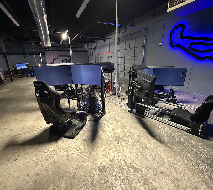 Gaming setup with racing seats and multiple monitors in an industrial-style room