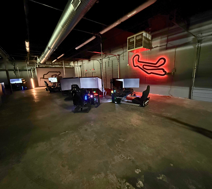 Indoor garage with three small vehicles parked under a red neon airplane sign.
