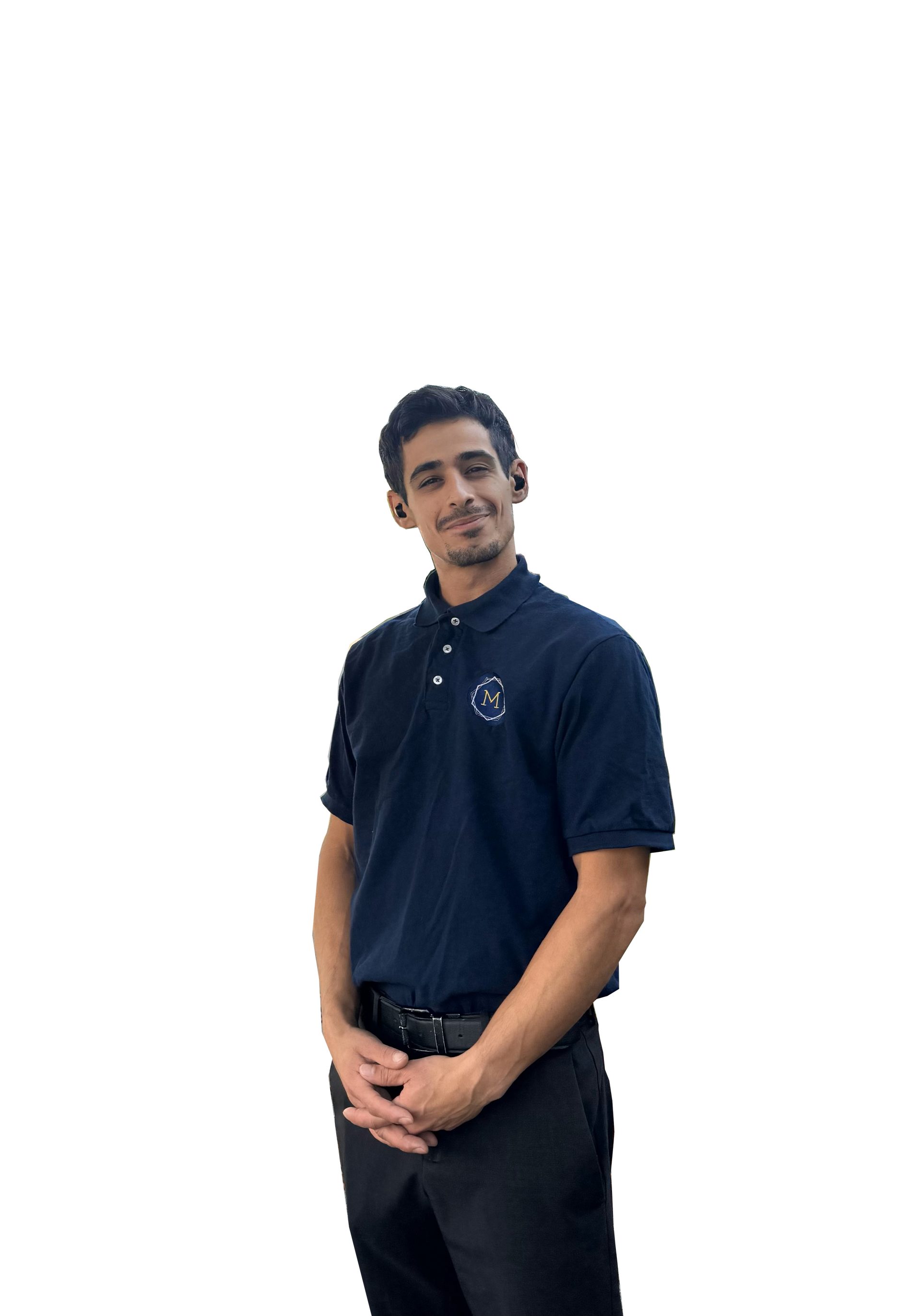 Person standing against a white background, wearing a dark navy shirt and black pants, hands clasped.