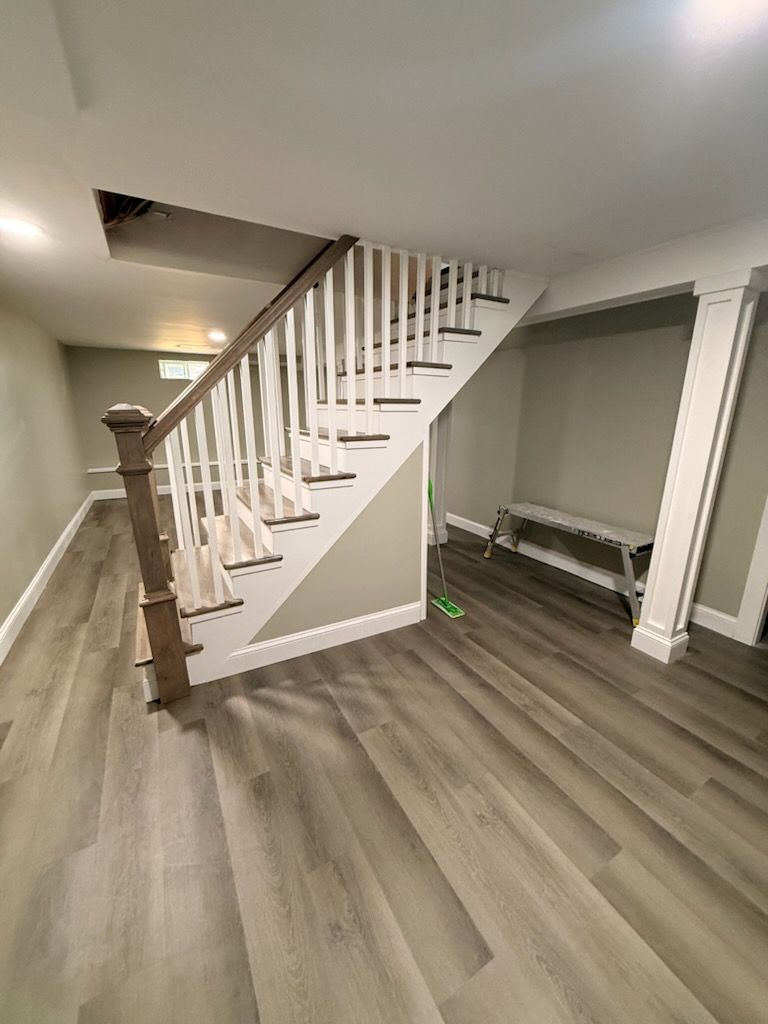 Interior staircase with white railings, wood floor, and a small bench under the stairs.