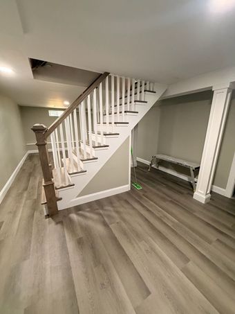 Interior staircase with white railings, wood floor, and a small bench under the stairs.