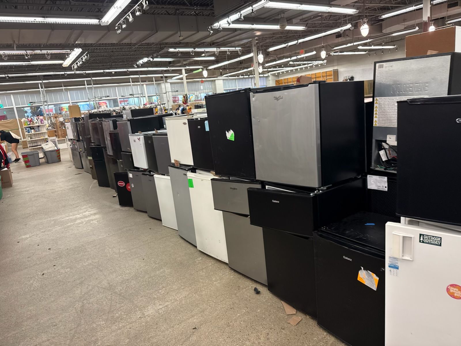 Rows of dorm refrigerators under fluorescent lights