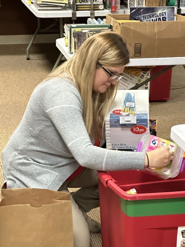 A woman is kneeling down in front of a red bin.