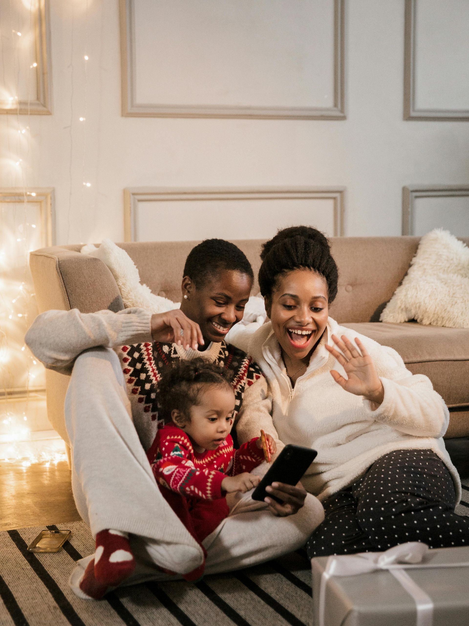 A family is sitting on the floor looking at a cell phone.