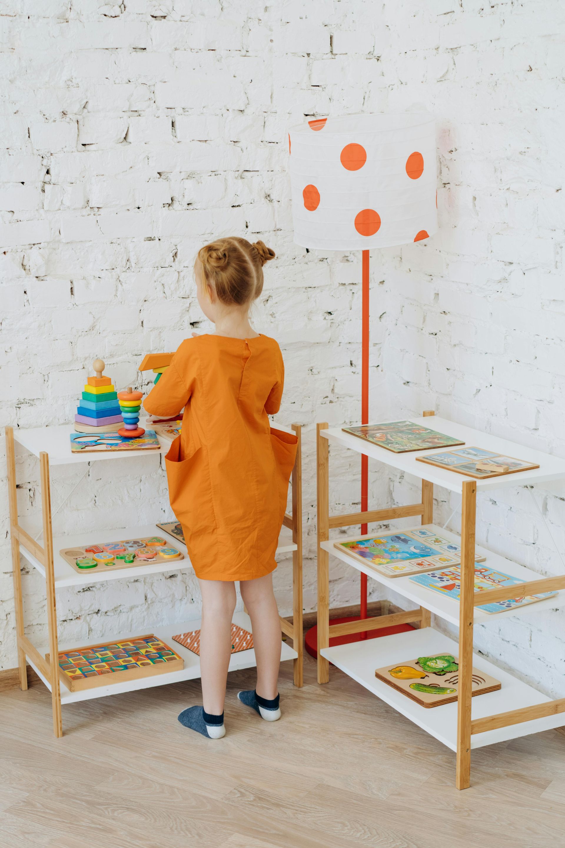 A little girl is standing in a room playing with toys.