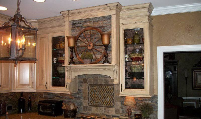 Kitchen with ornate stone range hood, decorative wheel, glass cabinets, and hanging lantern light fixtures