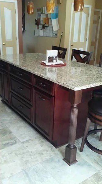 Kitchen island with dark wood cabinets and granite countertop in a tiled room