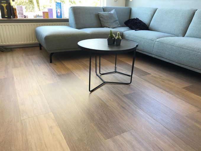 Modern living room with a gray sectional sofa, round coffee table, and wood flooring