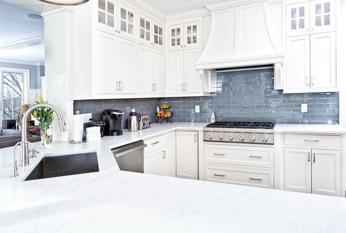Bright white modern kitchen with blue tile backsplash, stainless steel stove, and large white island