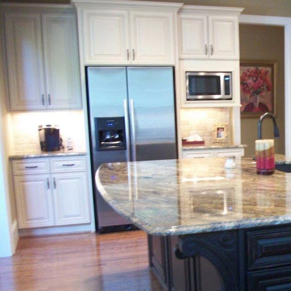 Modern kitchen with white cabinets, stainless steel appliances, and a large granite island