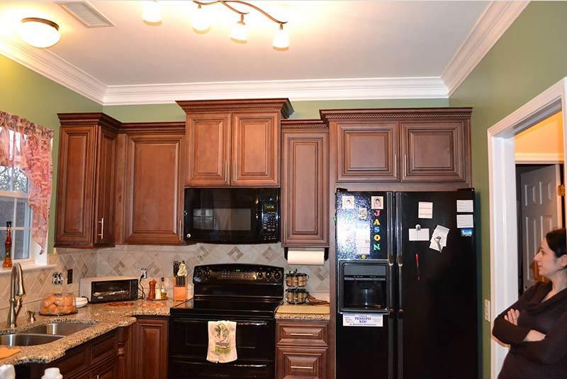 Kitchen with dark wood cabinets, black appliances, and a woman standing near the refrigerator