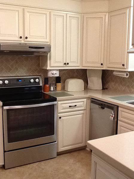 Small white kitchen with stove, cabinets, countertop appliances, and a dishwasher.