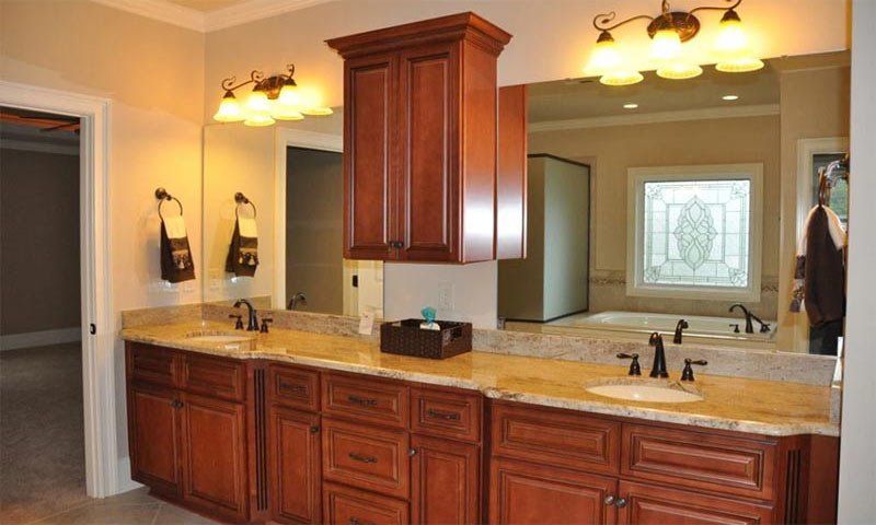 Spacious bathroom with double vanity, wood cabinets, granite countertop, and wall sconces