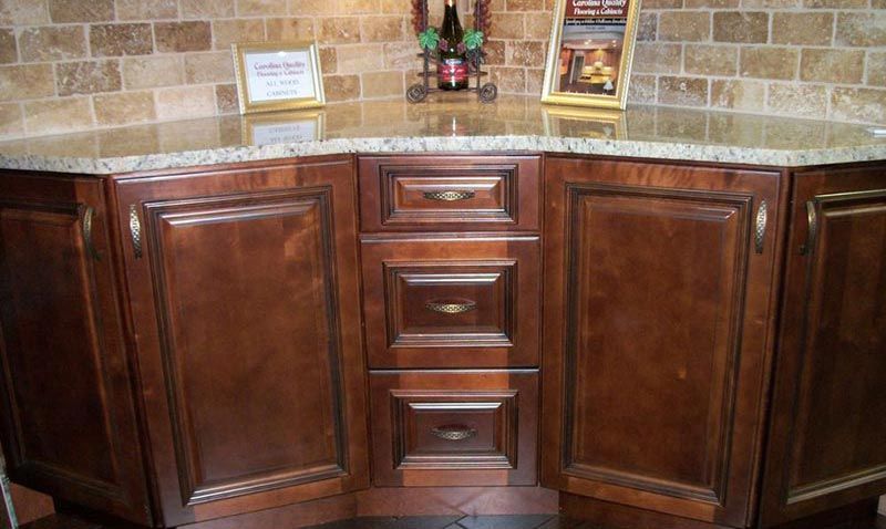 Dark wood kitchen cabinet with drawers, framed by stone tile backsplash and countertop items